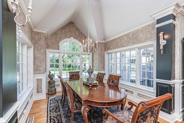 dining room featuring high vaulted ceiling, a chandelier, light hardwood / wood-style flooring, and crown molding