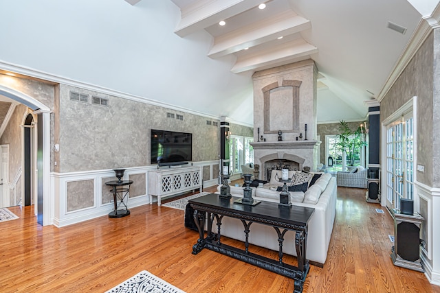 living room with a high end fireplace, a towering ceiling, light hardwood / wood-style floors, and beamed ceiling