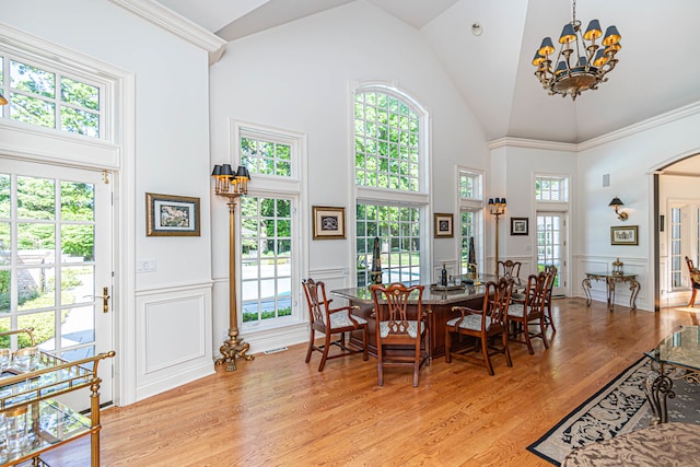 dining space with high vaulted ceiling, light wood-type flooring, and a notable chandelier