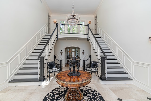 foyer entrance with a notable chandelier, light tile flooring, and crown molding