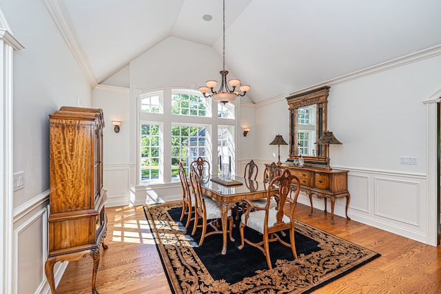 dining area with a notable chandelier, vaulted ceiling, ornamental molding, and light hardwood / wood-style flooring