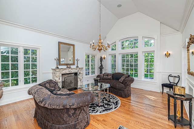 living room with a chandelier, light hardwood / wood-style flooring, a fireplace, and ornamental molding