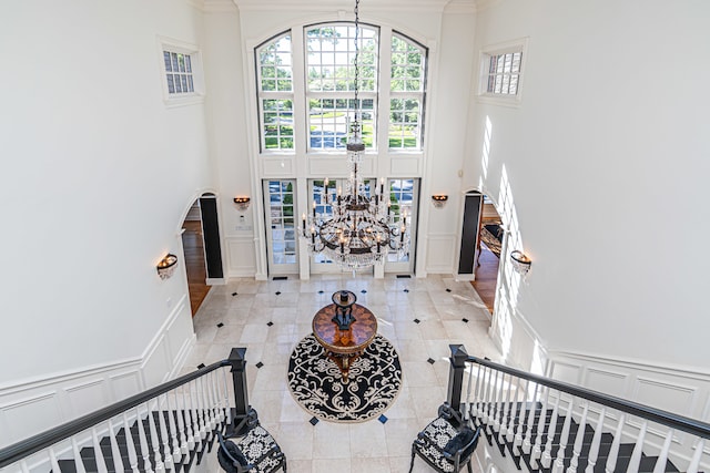 tiled foyer entrance with a high ceiling, a chandelier, and crown molding