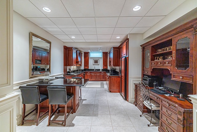 home office with sink, a paneled ceiling, and light tile floors