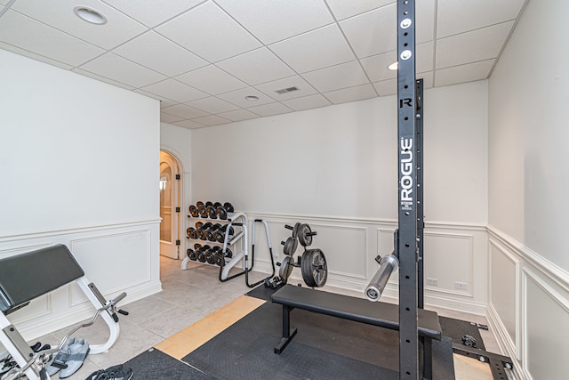 exercise area featuring light tile flooring and a drop ceiling