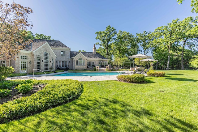 view of pool with a patio area and a lawn