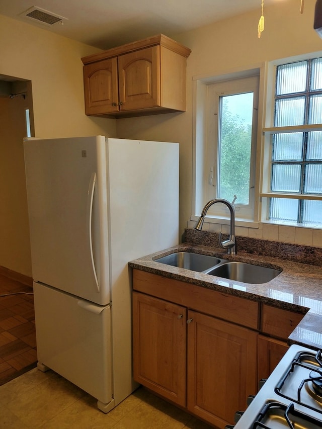 kitchen featuring white refrigerator, sink, and light tile floors