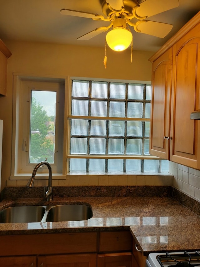 kitchen featuring backsplash, sink, dark stone counters, and ceiling fan