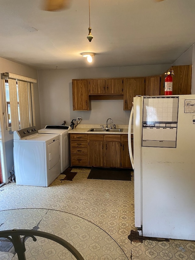 kitchen with pendant lighting, white refrigerator, separate washer and dryer, and sink