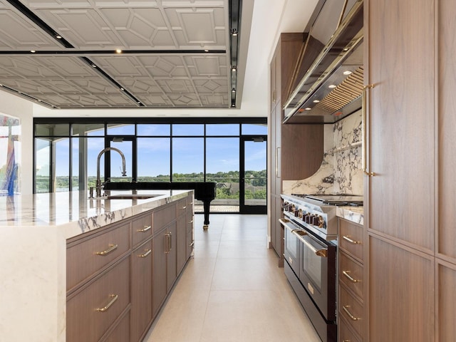 kitchen with light stone countertops, a sink, an ornate ceiling, double oven range, and custom exhaust hood