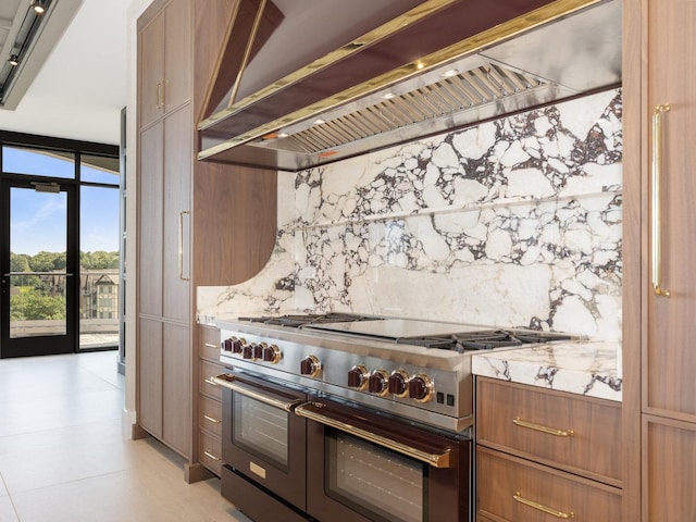 kitchen with brown cabinetry, backsplash, double oven range, and extractor fan