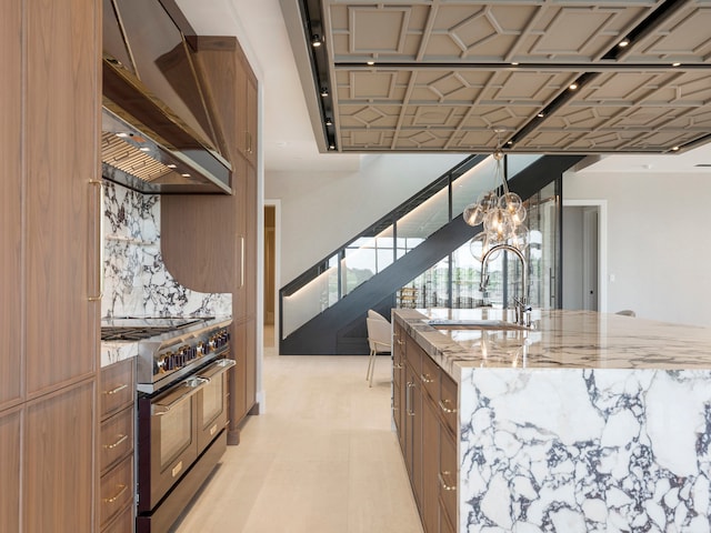 kitchen with gas range oven, sink, backsplash, a chandelier, and custom range hood