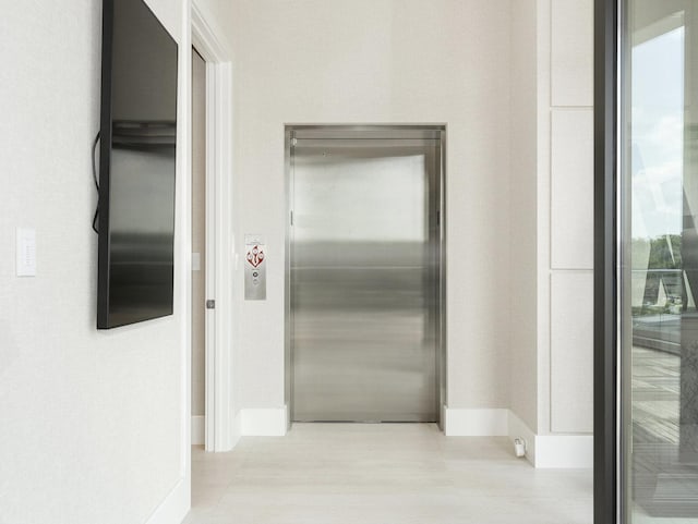 hallway with baseboards and elevator