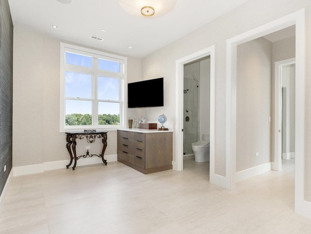 bedroom with baseboards, visible vents, light tile patterned floors, and ensuite bathroom