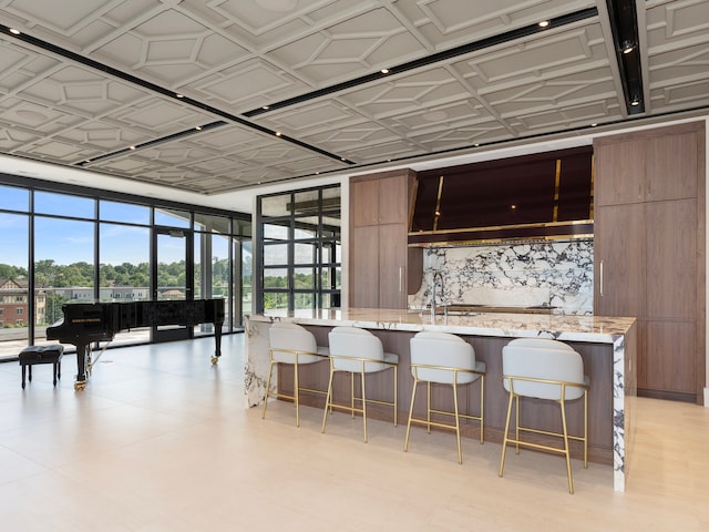 kitchen with light stone counters, a breakfast bar area, and a kitchen island with sink