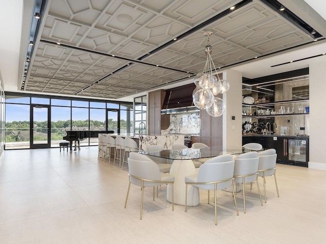 dining area with expansive windows, an ornate ceiling, a chandelier, wine cooler, and bar area