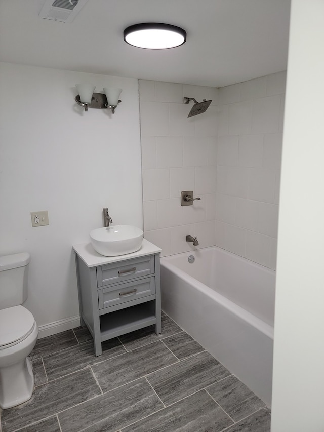 full bathroom featuring tiled shower / bath, vanity, and toilet