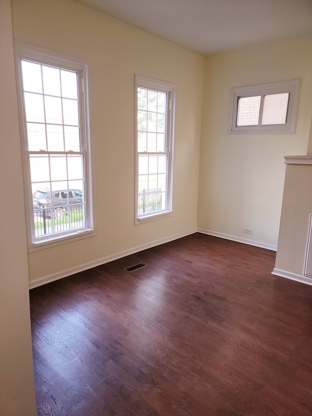 empty room with dark hardwood / wood-style flooring and a healthy amount of sunlight