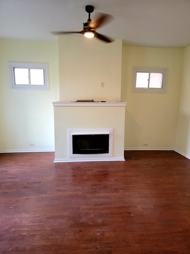 unfurnished living room featuring dark wood-type flooring and ceiling fan