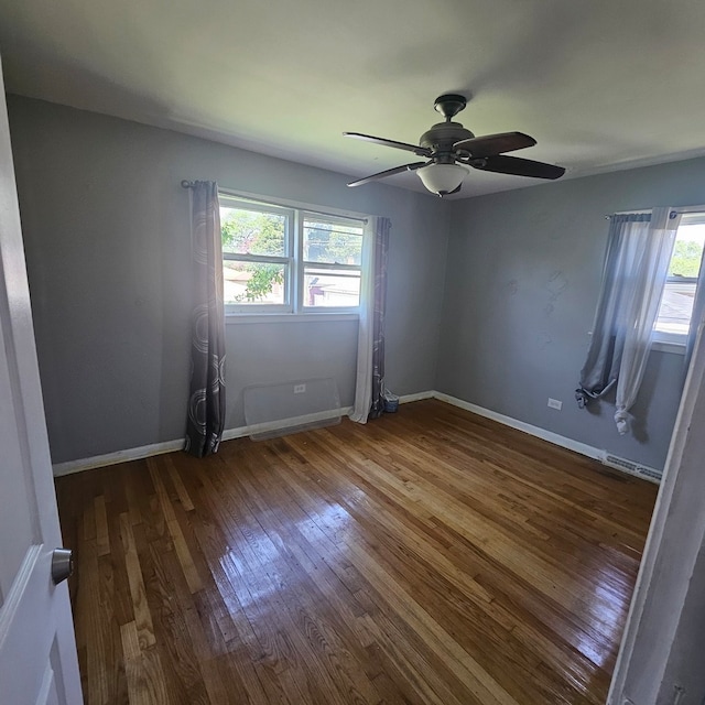 empty room featuring ceiling fan, a healthy amount of sunlight, and hardwood / wood-style floors