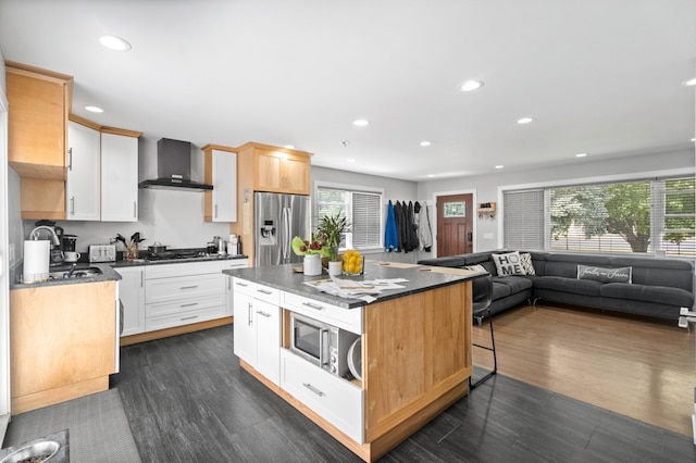 kitchen with a kitchen island, dark hardwood / wood-style flooring, stainless steel appliances, wall chimney exhaust hood, and a healthy amount of sunlight