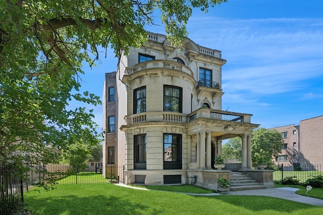 back of house with a lawn and a balcony