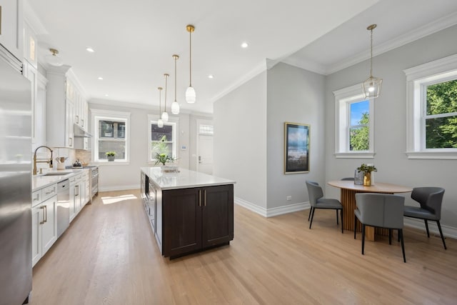 kitchen with white cabinets, a kitchen island, crown molding, and hanging light fixtures