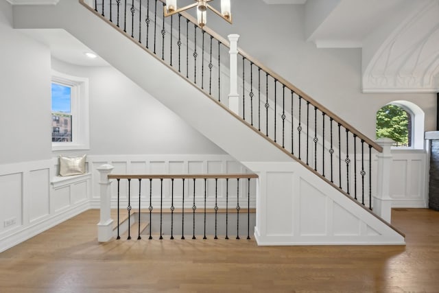 stairs with hardwood / wood-style floors, a notable chandelier, and a wealth of natural light