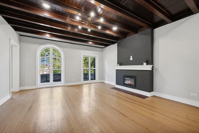 unfurnished living room with beamed ceiling, light wood-type flooring, and wooden ceiling