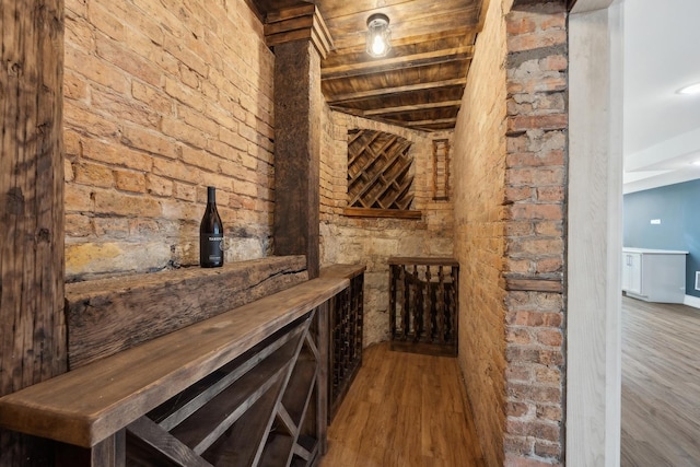 wine room with hardwood / wood-style flooring, wood ceiling, beamed ceiling, and bar area