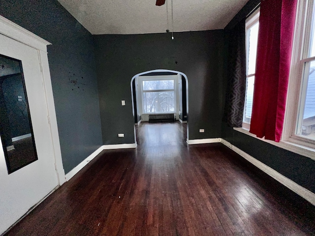 spare room with ceiling fan, dark hardwood / wood-style floors, and radiator heating unit