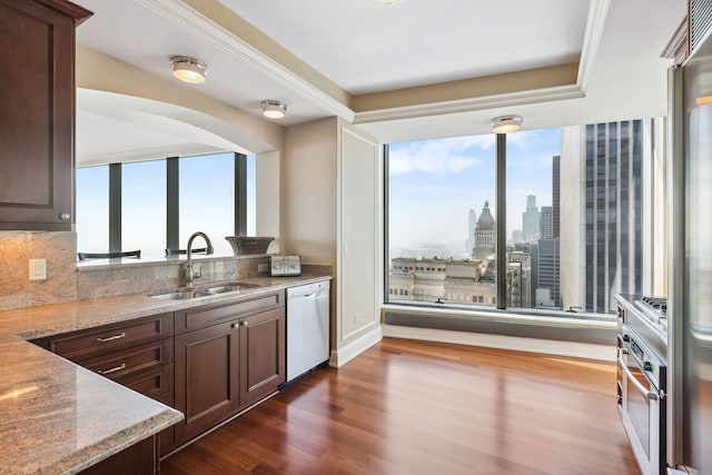 kitchen featuring light stone countertops, dark brown cabinets, white dishwasher, and sink