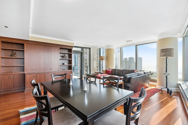 dining room featuring wood-type flooring, expansive windows, and crown molding