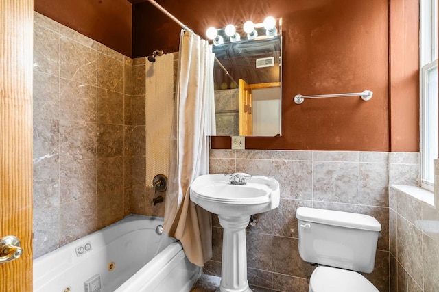 bathroom with shower / bath combination with curtain, tile walls, and toilet