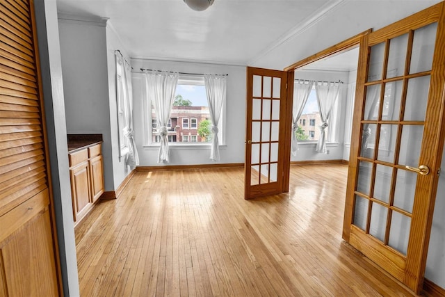 interior space featuring crown molding, light hardwood / wood-style flooring, and french doors