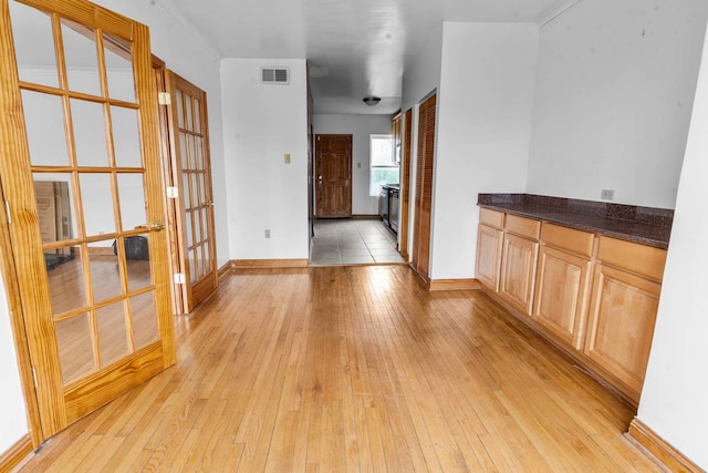 interior space featuring light hardwood / wood-style floors, dark stone countertops, light brown cabinets, and french doors