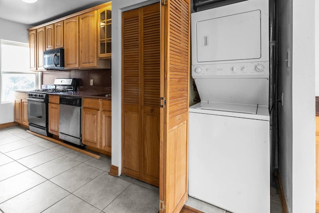 kitchen with light tile patterned floors, stacked washing maching and dryer, and appliances with stainless steel finishes