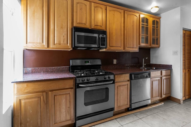 kitchen with dishwasher, light tile patterned flooring, dark stone counters, and range with gas stovetop