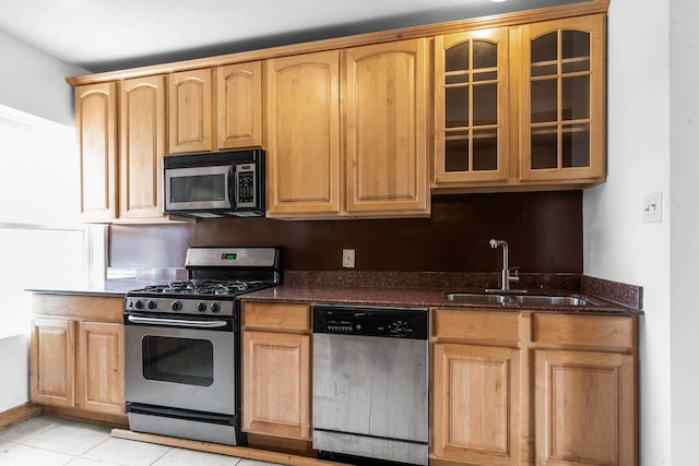 kitchen with light tile patterned flooring, sink, stainless steel appliances, and dark stone counters