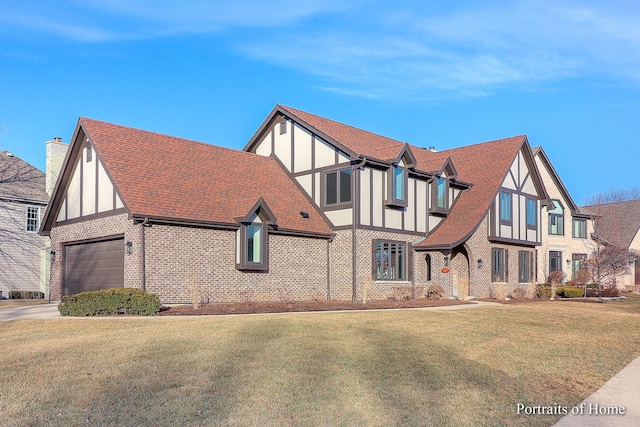 english style home featuring a garage and a front yard