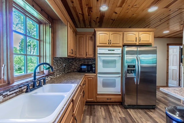 kitchen with dark hardwood / wood-style floors, white double oven, stainless steel fridge, and tasteful backsplash