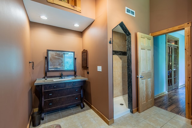 bathroom featuring a tile shower, tile flooring, and vanity