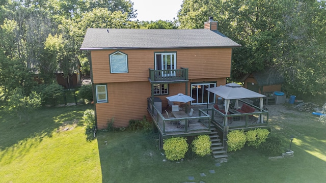 back of property featuring a wooden deck and a lawn