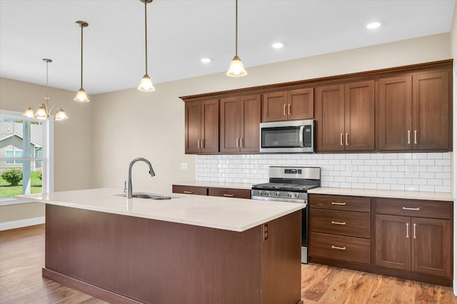 kitchen with sink, light hardwood / wood-style flooring, stainless steel appliances, and tasteful backsplash