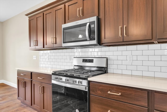 kitchen featuring stainless steel appliances, backsplash, and light wood-type flooring