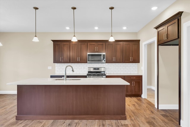 kitchen featuring light hardwood / wood-style flooring, backsplash, stainless steel appliances, hanging light fixtures, and sink