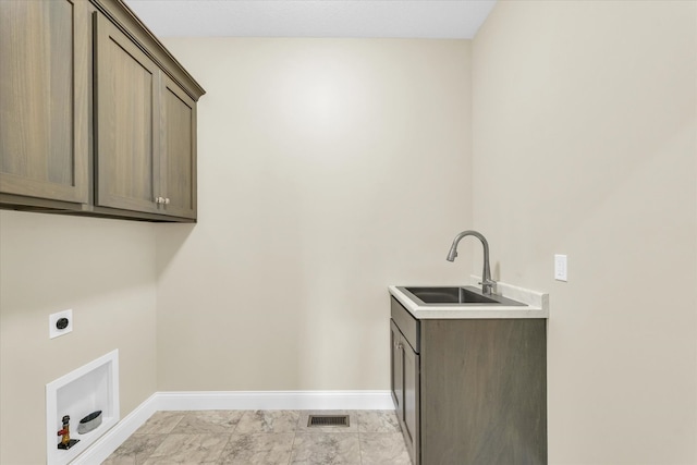 washroom with electric dryer hookup, sink, cabinets, and light tile patterned floors