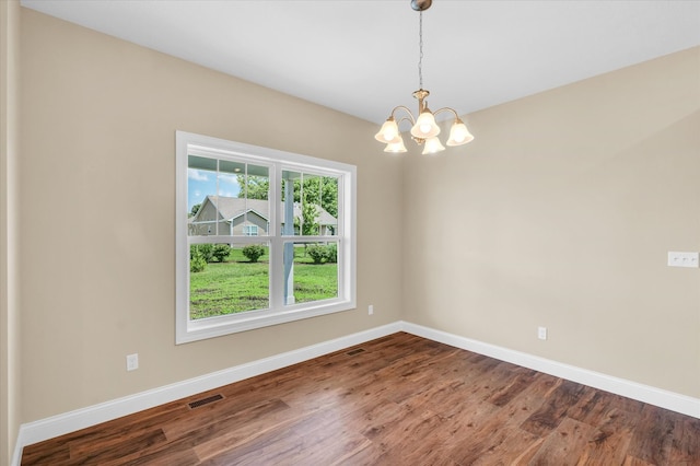 unfurnished room featuring an inviting chandelier and dark hardwood / wood-style floors