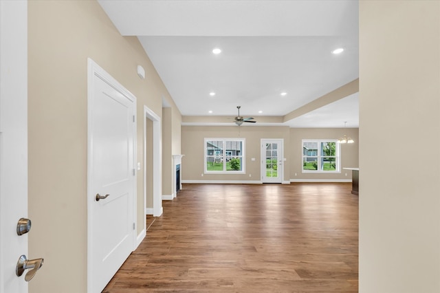 unfurnished living room featuring wood-type flooring and ceiling fan with notable chandelier