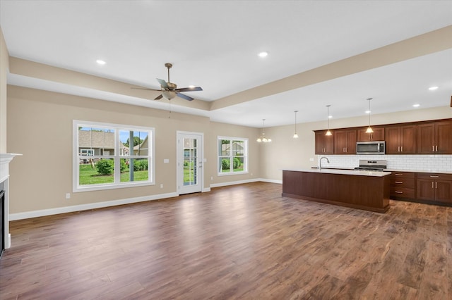 kitchen with ceiling fan, dark hardwood / wood-style flooring, pendant lighting, appliances with stainless steel finishes, and backsplash